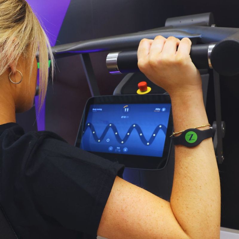 Woman working out on Shoulder Press and engaging with interactive screen